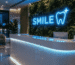 Dark scene with a glowing aqua blue neon sign reading SMILE