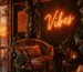 Dark scene with a glowing sunset orange neon sign reading Vibes