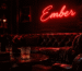 Dark scene with a glowing deep red neon sign reading Ember