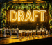 Dark scene with a glowing golden amber neon sign reading DRAFT