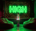 Dark scene with a glowing trippy green neon sign reading HIGH