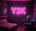Dark scene with a glowing silver pink neon sign reading Y2K