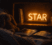 Dark scene with a glowing amber neon sign reading STAR